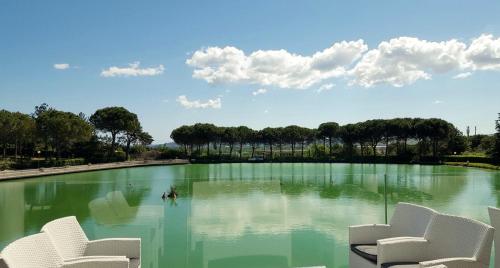 a large pool of water with white chairs in it at Villaggio La Pescaccia in San Clemente