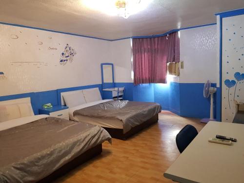 a room with two beds and a table and a window at San Ho Hotel in Taoyuan