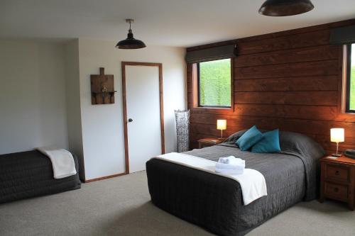 een slaapkamer met een bed met een houten muur bij Inn the Bay Bed & Breakfast in Kaikoura
