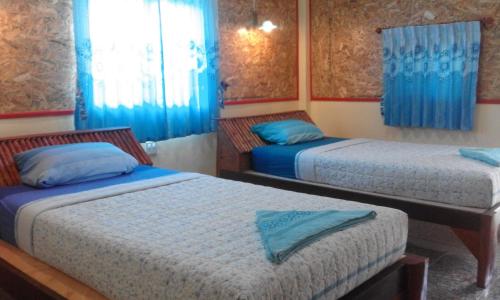 twee bedden in een kamer met blauwe gordijnen bij Relax Beach House in Koh Lanta