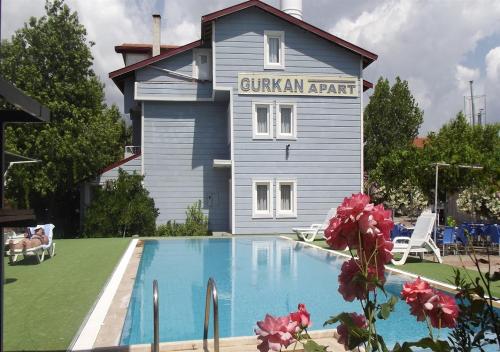 a building with a swimming pool in front of a house at Gurkan Apart Hotel in Dalyan