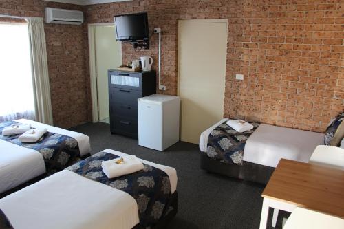 a hotel room with two beds and a brick wall at Motel 359 in Tamworth