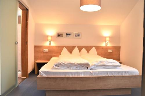 a bedroom with a large bed with white sheets at Appartements Pungg in Fügen