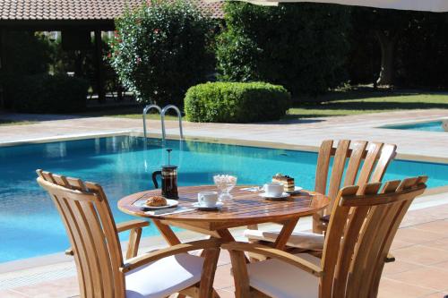 a wooden table and two chairs next to a pool at Efe Hotel Gocek in Göcek