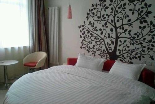a bedroom with a bed with a tree on the wall at Thank Inn Chain Hotel Jiangxi Yichun Fengcheng Dongfanghong Avenue in Fengcheng
