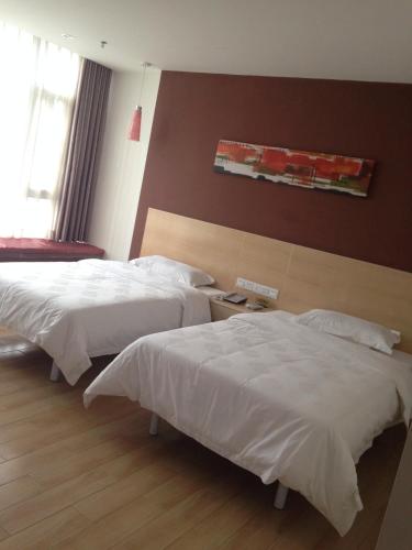 Cette chambre d'hôtel comprend 2 lits avec des draps blancs. dans l'établissement Thank Inn Chain Hotel Guangdong Heyuan East Longchuang Road, à Longchuan
