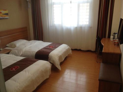 um quarto de hotel com duas camas e uma secretária e uma janela em Thank Inn Chain Hotel Hebei Langfang the 6th Street em Langfang