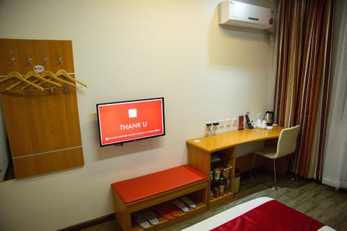 金昌市にあるThank Inn Chain Hotel Gansu Jinchang Heya Roadのデスク、壁のモニターが備わる客室です。