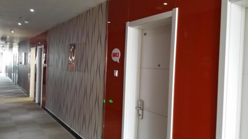 un pasillo con paredes rojas y una puerta abierta en Thank Inn Chain Hotel Hebei Cangzhou Qing County Nanhuan Road en Qing