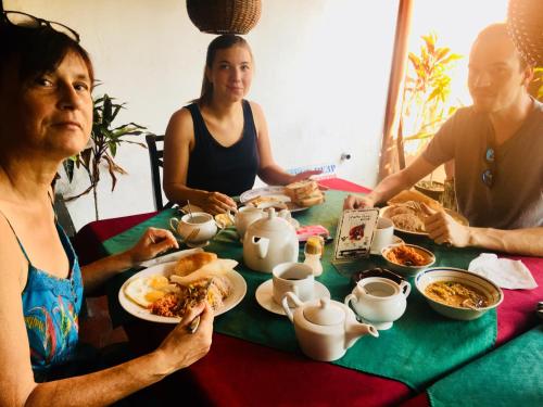 Un grupo de personas sentadas alrededor de una mesa comiendo comida en Casalanka Hotel, en Hikkaduwa
