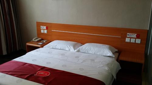 een slaapkamer met een bed met een houten hoofdeinde bij Thank Inn Chain Hotel Shanxi Lvliang County Taihe North Road in Houganquan