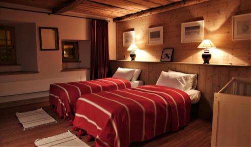 Cette chambre comprend 3 lits avec des draps rouges et blancs. dans l'établissement Chalet Geneviève, à Sainte-Foy-Tarentaise
