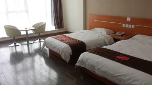 a hotel room with two beds and a table and chairs at Thank Inn Chain Hotel Shanxi Lvliang Lishi Beichuanghe Road in Luliang