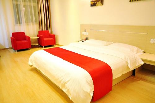 a bedroom with a large bed and two red chairs at Thank Inn Chain Hotel Shandong Zibo Zichuan Luzhong International Shopping mall in Zibo
