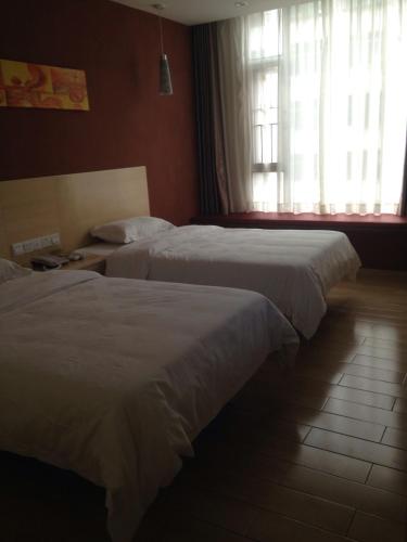 two beds in a hotel room with a window at Thank Inn Chain Hotel Guangdong Heyuan East Longchuang Road in Longchuan