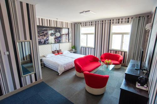 a bedroom with a bed and two red chairs at JUNYI Hotel Shandong Dezhou Xiajin County Jianshe Street in Xiajin