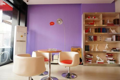 una mesa y sillas en una habitación con paredes púrpuras en Thank Inn Chain Hotel Hunan Loudi New Huaxuefu Road en Dongling