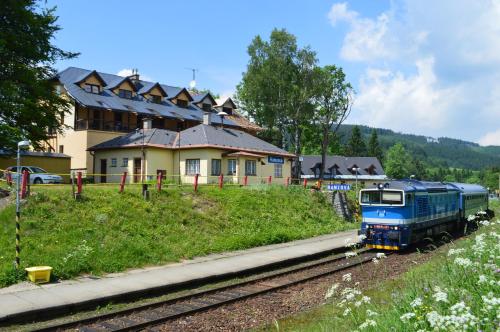 a blue train on the tracks in front of a house at Chata Ramzovské sedlo in Ramzová