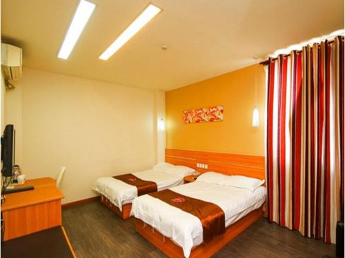 a hotel room with two beds and a television at Thank Inn Chain Hotel Jiangsu Wuxi Xishan District Leather City in Dongbeitang