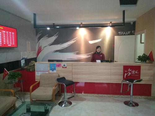 a woman standing behind a counter in a waiting room at Thank Inn Chain Hotel Shandong Dezhou Decheng District Wanda Plaza in Dezhou