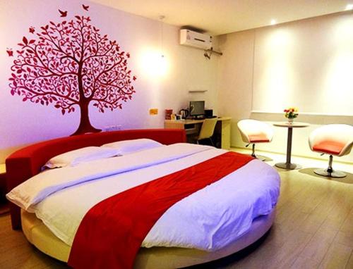 een slaapkamer met een bed met een boom aan de muur bij Thank Inn Chain Hotel Gansu Pingliang West Huating Street Zhaozhuang in Khuatin