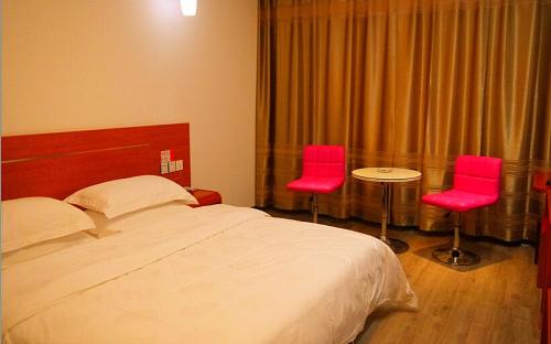 une chambre d'hôtel avec un lit et deux chaises roses dans l'établissement Thank Inn Chain Hotel Henan Anyang Linzhou Bus Station Taoyuan Avenue, à Linzhou