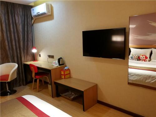 Thank Inn Chain Hotel Shandong Qingdao Development Zone 2nd Xiangjiang Road في Yantaiqian: غرفة في الفندق مع مكتب وتلفزيون على الحائط