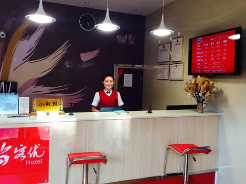 Eine Frau, die hinter einem Tresen in einem Restaurant steht. in der Unterkunft Thank Inn Chain Hotel Henan Xuchang Railway Station Qiyi Road in Xuchang