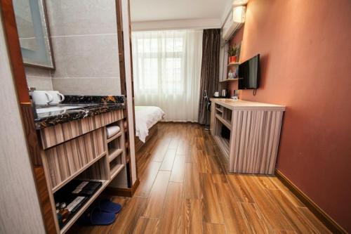 a small room with a bed and a television at JUNYI Hotel Jiangsu Yancheng Tinghu District Jinying International Shopping Center in Yancheng