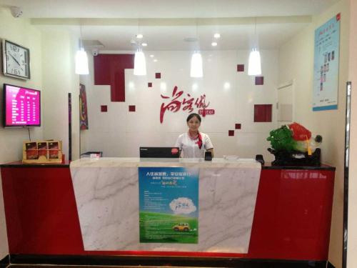 una mujer parada detrás de un mostrador en un restaurante en Thank Inn Chain Hotel Hebei Langfang Guan Bus Station, en Liuquan