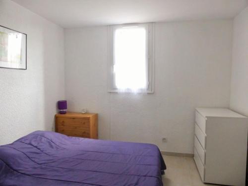 um quarto com uma cama roxa e uma janela em 3CPF29 Appartement avec jardinet et parking, proche centre-ville em Collioure