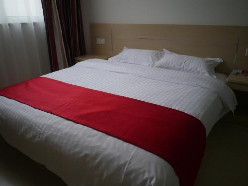 Thank Inn Chain Hotel Jiangsu Nantong Jiuwei Bay في نانتونغ: سرير ابيض كبير وعليه خط احمر