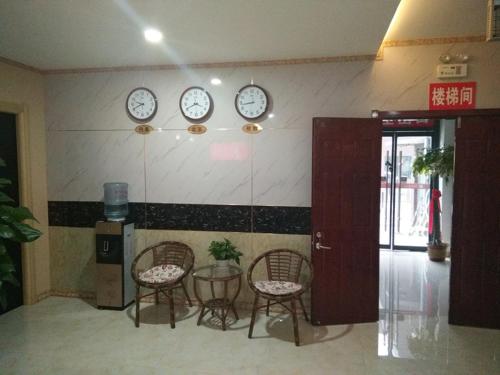 um quarto com duas cadeiras e relógios na parede em Thank Inn Chain Hotel Shandong Dezhou Decheng District Wanda Plaza em Dezhou