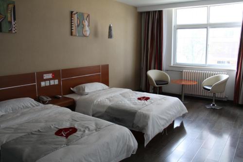a hotel room with two beds and a window at Thank Inn Chain Hotel Shandong Liaocheng Economic Development Zone Jiuhe Community in Liaocheng