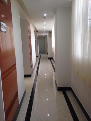 - un couloir dans un bâtiment doté de murs blancs et de carrelage dans l'établissement Thank Inn Chain Hotel Guangdong Heyuan East Longchuang Road, à Longchuan