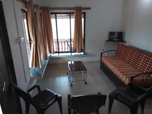 een woonkamer met een bank, stoelen en een tafel bij Nivaant in Dapoli