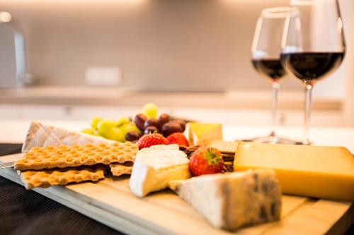 a plate of cheese and fruit with a glass of wine at Wellness Hasselt B&B in Hasselt
