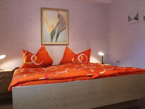 a bedroom with a bed with an orange comforter at Peaceful Apartment in Klutz Germany near Boltenhagener Beach in Klütz
