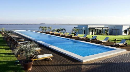 a large swimming pool with lounge chairs and a house at Casa Chic Carmelo - Club de Campo in Carmelo