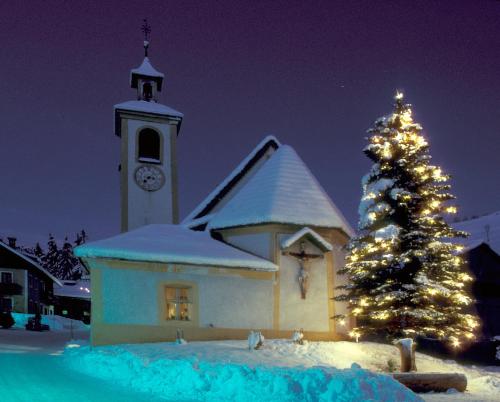 una iglesia con un árbol de Navidad y una torre del reloj en Gasthof Huber en Braies