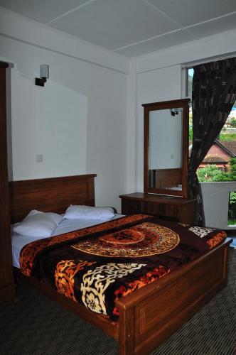 Un dormitorio con una cama con espejo y una ventana. en Coolborn Apartment, en Nuwara Eliya