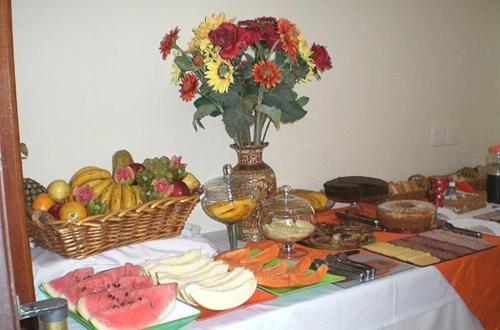 een tafel met fruit en wijnglazen en een vaas met bloemen bij Hotel Casarão in Peruíbe