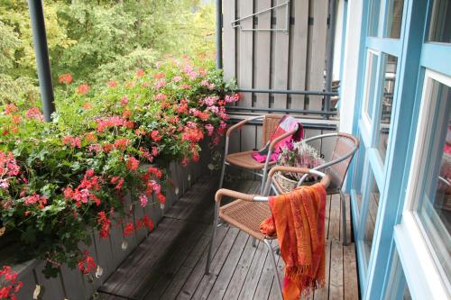 a porch with two chairs and flowers on a balcony at Hotel Bannwaldsee in Halblech