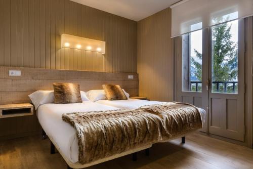 Un dormitorio con una cama grande con una manta de piel de imitación en Hotel Tobazo, en Candanchú