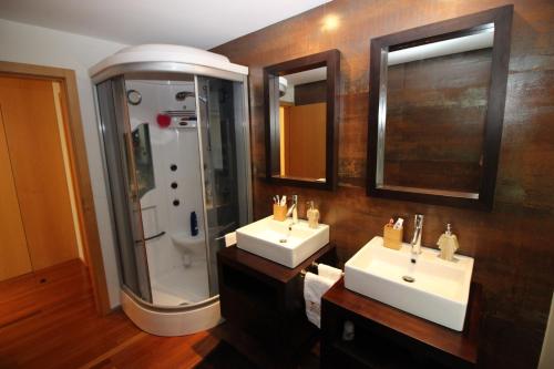 a bathroom with two sinks and a shower and two mirrors at Casa de Paredes Secas by Gerês Casas in Amares