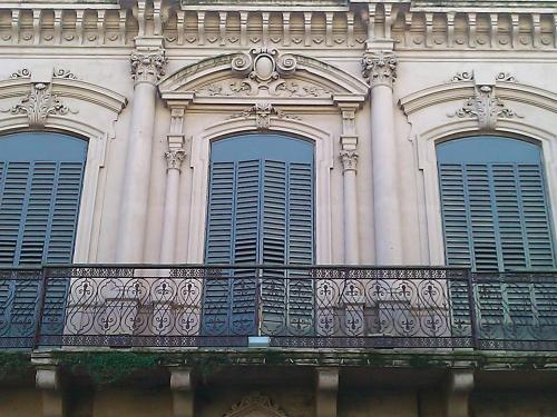 um edifício com três janelas e uma varanda em Montevideo Chic Hostel em Montevidéu