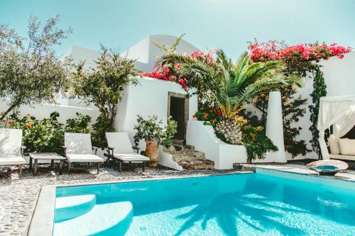 a pool in the backyard of a house with flowers at Santorini Heritage Villas in Megalochori