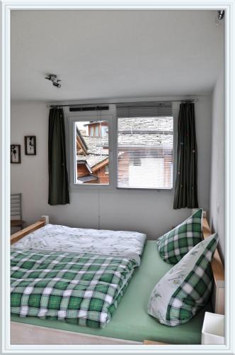 a bedroom with a green and white bed and a window at Chesa Tre Piz, Maloja in Maloja