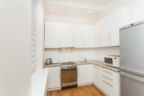 a white kitchen with white cabinets and a refrigerator at Donelaičio 42 in Kaunas