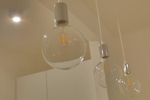 Cuasso Al MonteにあるVoi da Noi - Home Experienceの天井から吊るされる三本の透明なガラスの花瓶